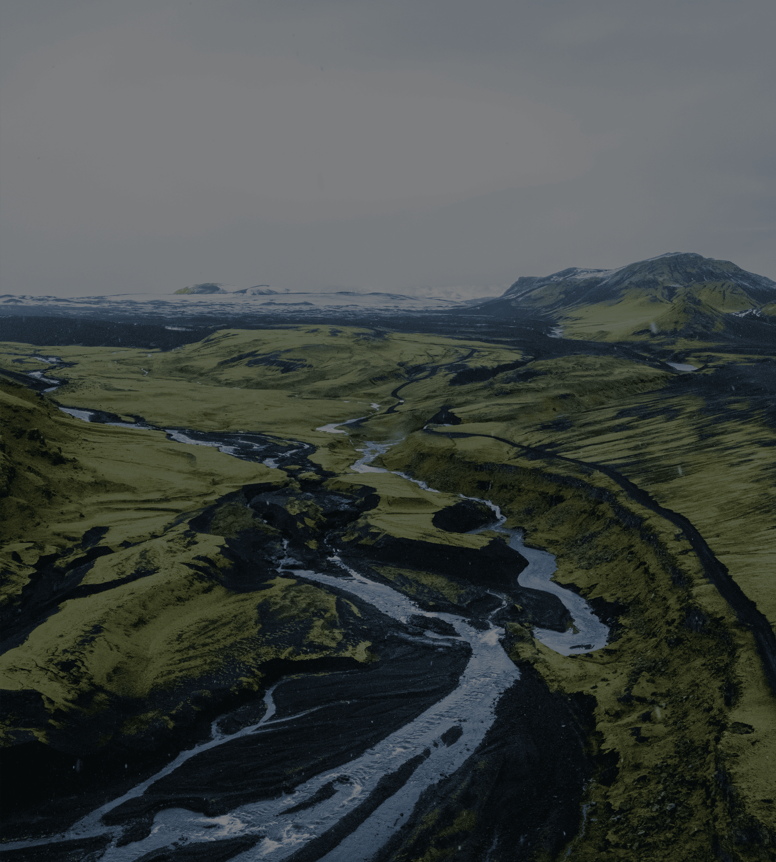 A glacial river braiding across a green valley, seen from the air