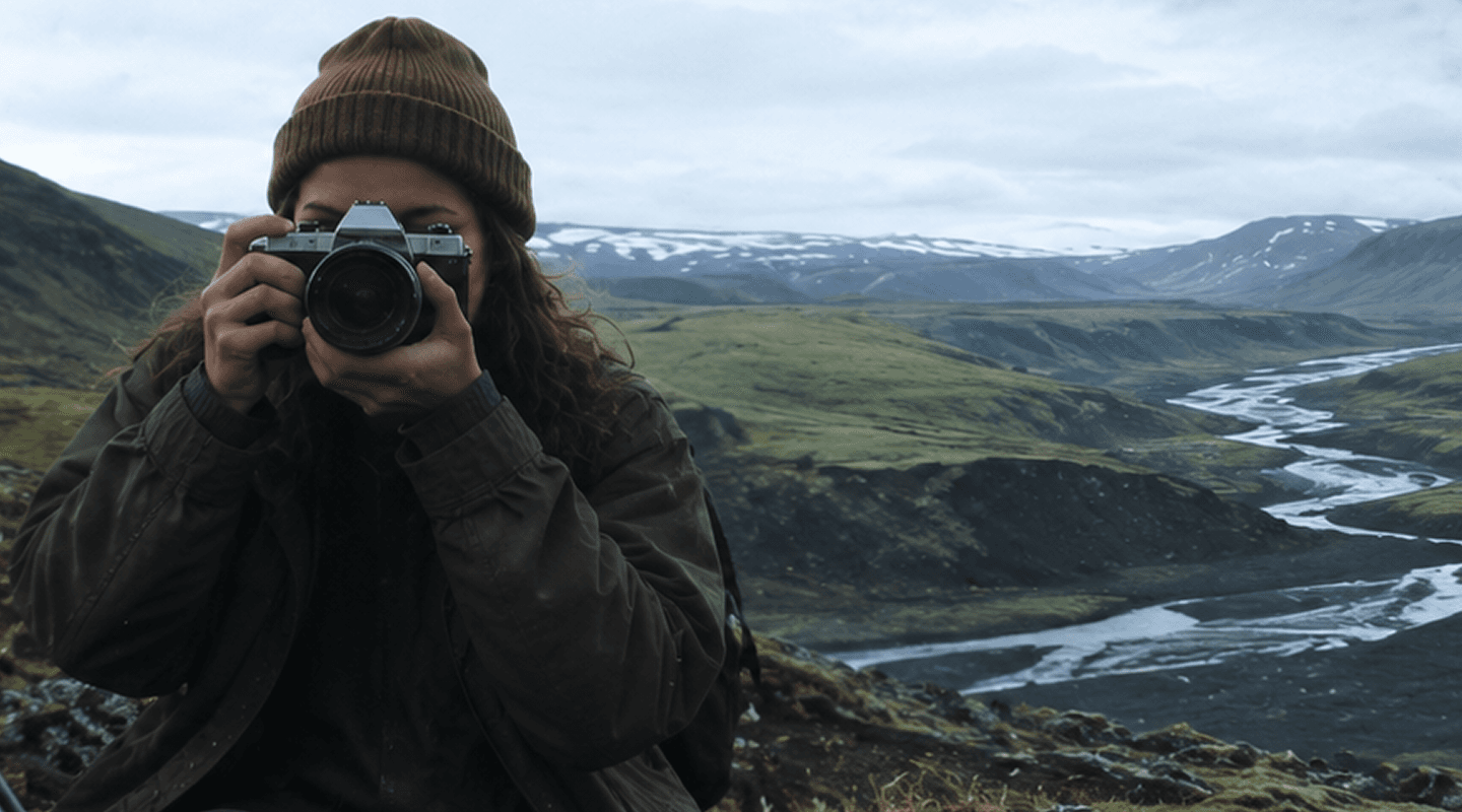 A traveller raising a camera over a glacial river valley